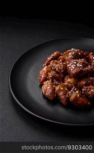 Chicken hearts fried in soy sauce with salt and spices in a plate on a textured concrete background