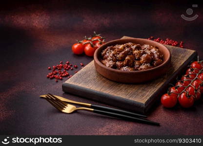 Chicken hearts fried in soy sauce with salt and spices in a plate on a textured concrete background