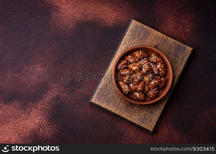 Chicken hearts fried in soy sauce with salt and spices in a plate on a textured concrete background