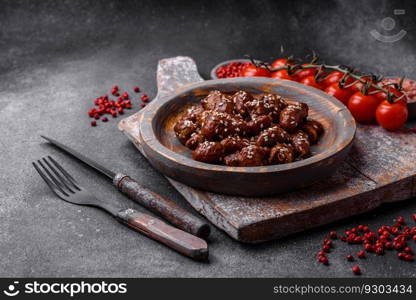 Chicken hearts fried in soy sauce with salt and spices in a plate on a textured concrete background