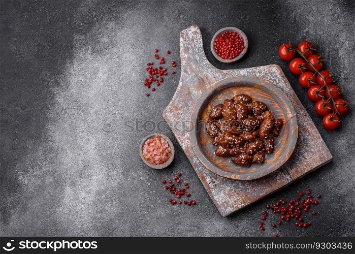Chicken hearts fried in soy sauce with salt and spices in a plate on a textured concrete background