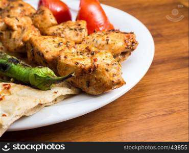 chicken kebabs with flatbread, tomato and pepper