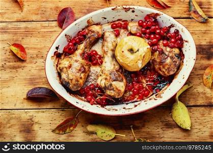 Chicken legs baked in a baking dish with apple and berries. Autumn meat recipe.. Chicken legs baked with apples and rowan