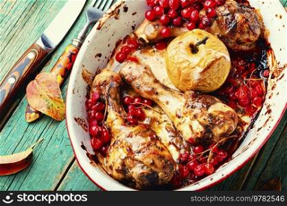 Chicken legs baked with apples and berries. Fried chicken meat in the oven dish. Chicken legs roasted with apples and rowan