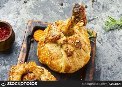Chicken legs in pastry.Chicken leg in puff pastry on cutting board.Baked chicken drumsticks on cutting board. Chicken leg baked in dough