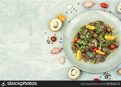 Chicken liver fried with mushrooms and tomatoes. Tasty liver in Georgian.Copy space. Delicious chicken liver, flat lay