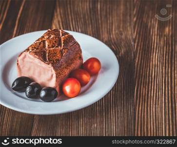 Chicken liver pate with black olives and cherry tomatoes on the white plate