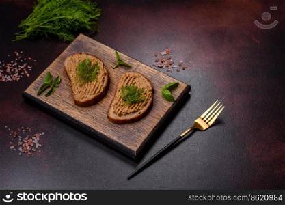 Chicken liver pate with bread on a wooden board over concrete background. Homemade meat snack liver pate with toast on a dark concrete background