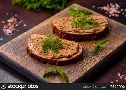 Chicken liver pate with bread on a wooden board over concrete background. Homemade meat snack liver pate with toast on a dark concrete background