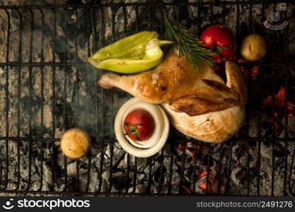 chicken meat with vegetables on a metal grill lay on charcoal. the dish is cooked and smoked on charcoal. a dish on cold coals