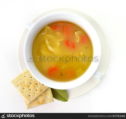 Chicken noodle soup in a white cup with crackers