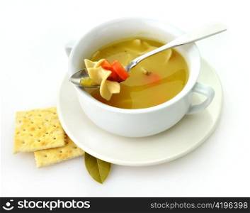 Chicken noodle soup in a white cup with crackers