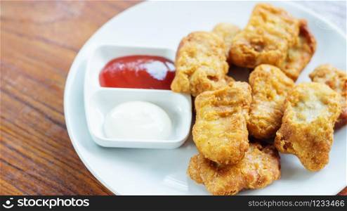 chicken nuggets, ketchup and mayonnaise on a white plate.