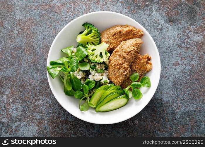 Chicken nuggets with fresh corn salad, broccoli, cucumber and rice, top view