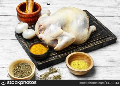 Chicken on the kitchen table. Raw chicken prepared for cooking and set of savory spices for meat