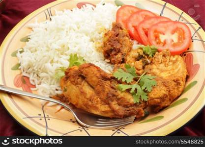 Chicken pieces marinaded in spice mix and tomato ketchup, then fried with garlic and ginger and finished with lemon and coriander leaf garnish, served with sliced tomatoes and boiled basmati rice.