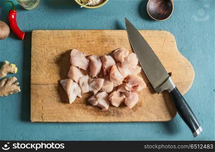 Chicken pieces on cutting board with knife on kitchen table , top view. Cooking preparation
