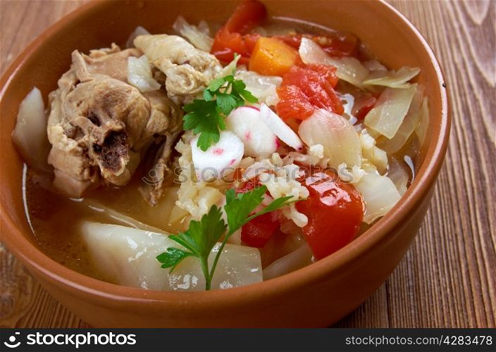 chicken posole garnished with carrots, tomato and radish.