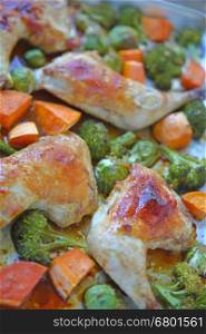 Chicken quarters roasting with broccoli, brussels sprouts and yam pieces