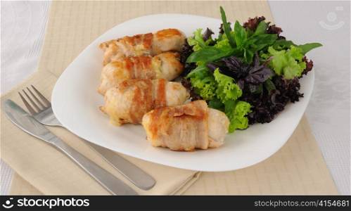 Chicken rolls stuffed with cheese, wrapped in bacon and herbs in a tomato-garlic sauce