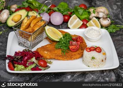 Chicken schnitzel with butter and potato salad on white porcelain plate