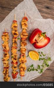 Chicken skewers with peppers, onion and sauteed carrots on the wooden background. Top view