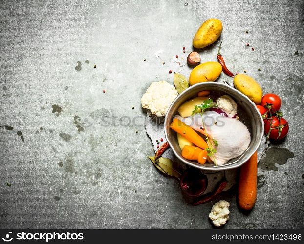 Chicken soup in an old pot with vegetables. On the stone table.. Chicken soup in an old pot with vegetables.