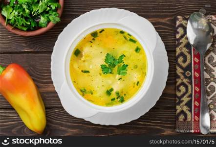 Chicken soup on wooden background, top view. Healthy wholesome food. Flat lay. Ingredients next to the plate.. Chicken soup on wooden background, top view. Healthy wholesome food. Flat lay