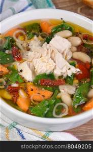 chicken soup with beans, spinach, tomatoes and other vegetables