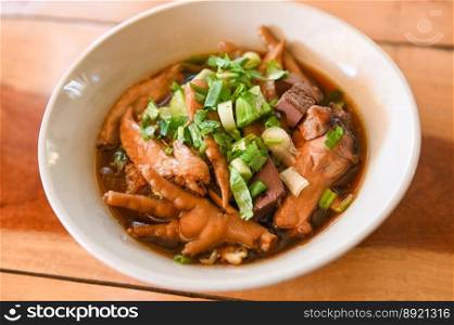 chicken soup with chicken leg feet and wings in red soup bowl and vegetable spring onion - stewed with chinese herbs