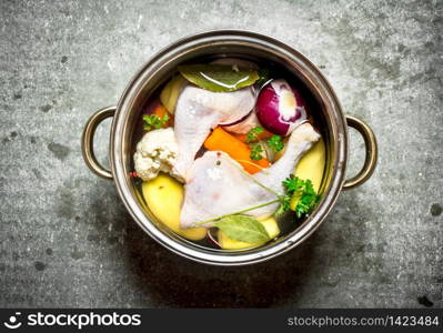 Chicken soup with fresh vegetables. On the stone table.. Chicken soup with fresh vegetables.