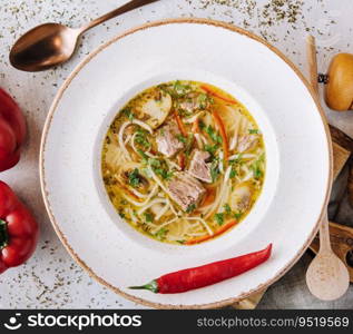 Chicken soup with noodles and vegetables in white bowl