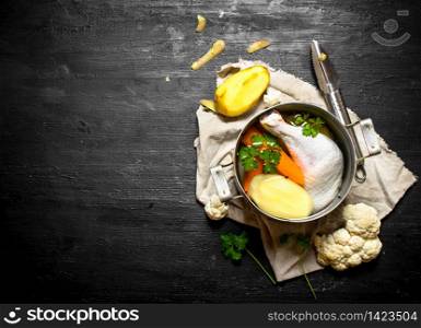 Chicken soup with potatoes, carrots and spices. On a black wooden background.. Chicken soup with potatoes, carrots and spices.
