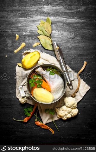 Chicken soup with potatoes, carrots and spices. On a black wooden background.. Chicken soup with potatoes, carrots and spices.