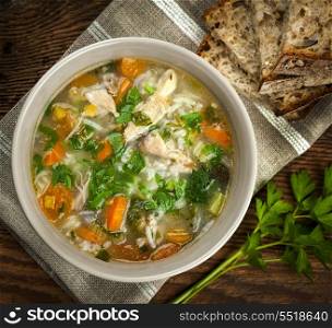Chicken soup with rice and vegetables. Chicken rice soup with vegetables in bowl and bread from above closeup