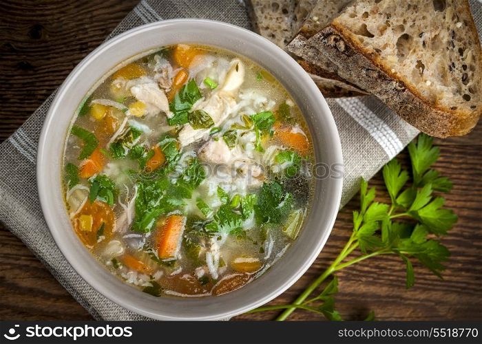Chicken soup with rice and vegetables. Chicken rice soup with vegetables in bowl and bread from above