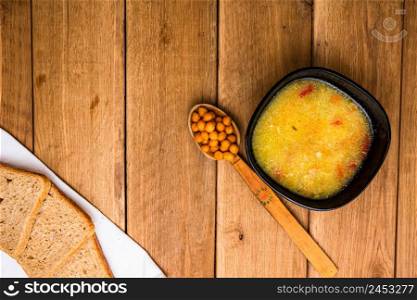 Chicken soup with sour cream, wholegrain toast on white napkin and croutons for lunch over wooden table, top view, copy space, lunch concept