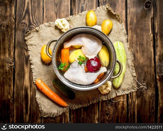 Chicken soup with vegetables in a large pot. On a wooden table.. Chicken soup with vegetables in a large pot.