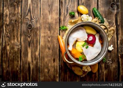 Chicken soup with vegetables in a large pot. On a wooden table.. Chicken soup with vegetables in a large pot.