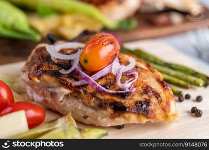 Chicken steak placed on a wooden tray with bell peppers, tomatoes, red onions, pineapple sauce, lettuce, and sesame seeds