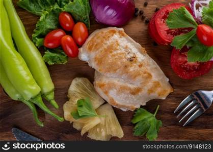 Chicken steak placed on a wooden tray with bell peppers, tomatoes, red onions, pineapple sauce, lettuce, and sesame seeds