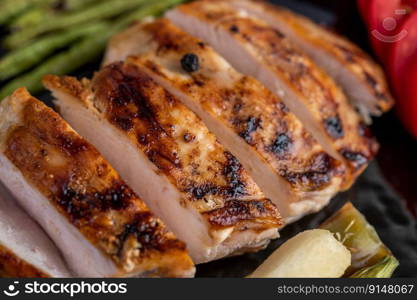 Chicken steak put on a black plate, add bell peppers, tomatoes, red onions, pineapple sauce, lettuce and sesame.