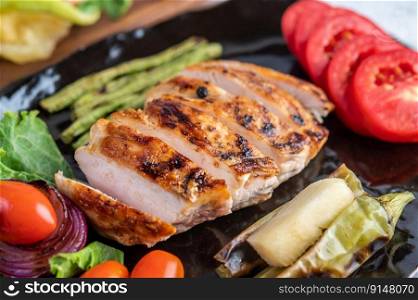 Chicken steak put on a black plate, add bell peppers, tomatoes, red onions, pineapple sauce, lettuce and sesame.