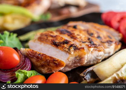 Chicken steak put on a black plate, add bell peppers, tomatoes, red onions, pineapple sauce, lettuce and sesame.