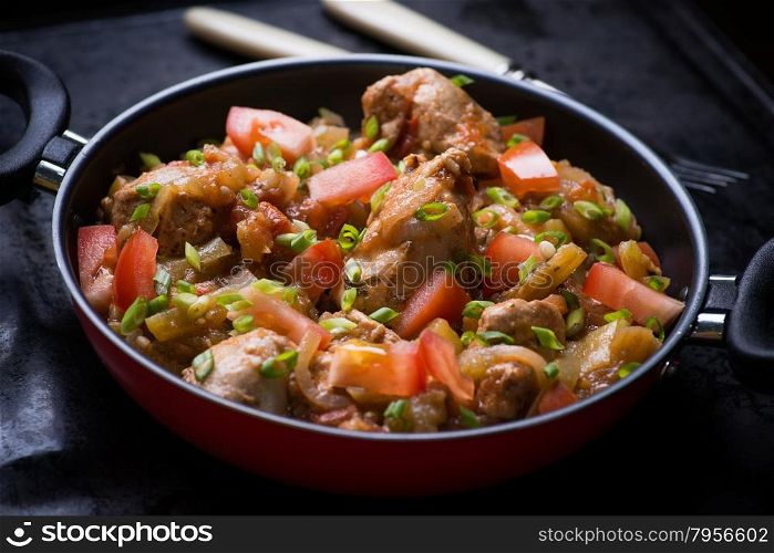 Chicken stew with onion, pepper ant tomato, selective focus, dark background