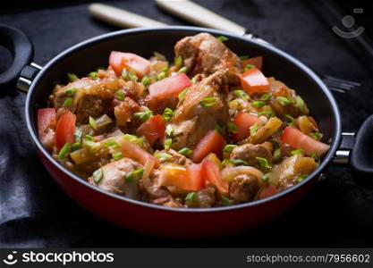 Chicken stew with onion, pepper ant tomato, selective focus, dark background