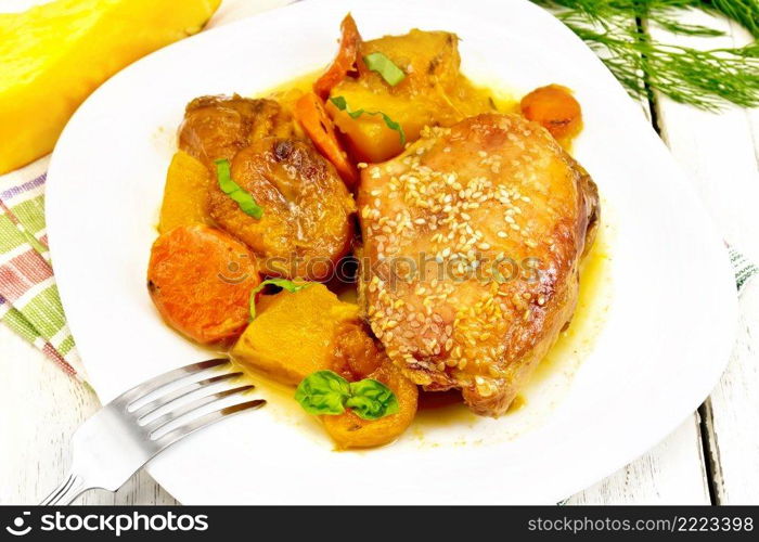 Chicken stew with pumpkin, dried apricots, carrots and red wine, sprinkled with sesame seeds in a dish on a kitchen towel against white wooden board