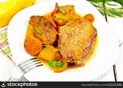 Chicken stew with pumpkin, dried apricots, carrots and red wine, sprinkled with sesame seeds in a dish on a kitchen towel against white wooden board