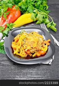 Chicken stewed with tomatoes, yellow and red bell peppers and cheese in a plate on napkin, thyme, parsley and garlic on wooden board background