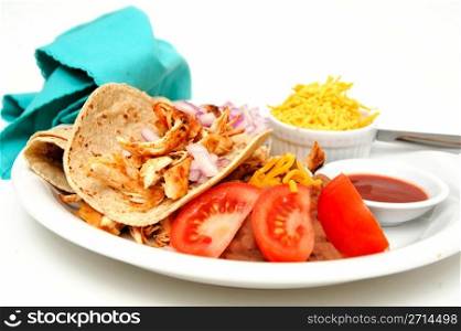 Chicken Taco. Shredded grilled spiced chicken on a white plate with fresh tortilla&rsquo;s, refried beans with sides of red onion, cheddar cheese and hot sauce.